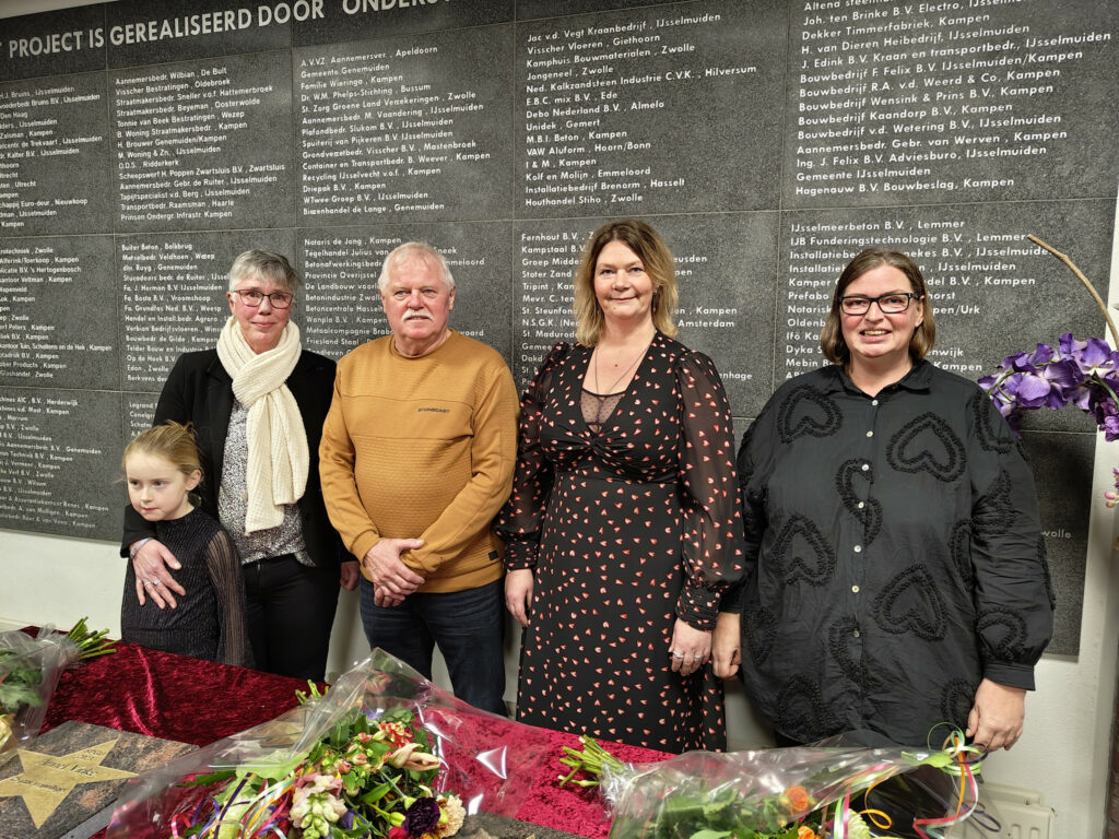 Vrijwilligers Annet (met kleindochter), Johan, Bianca en Wolanda poseren in de hal van de manege tijdens de viering van hun jubileum.