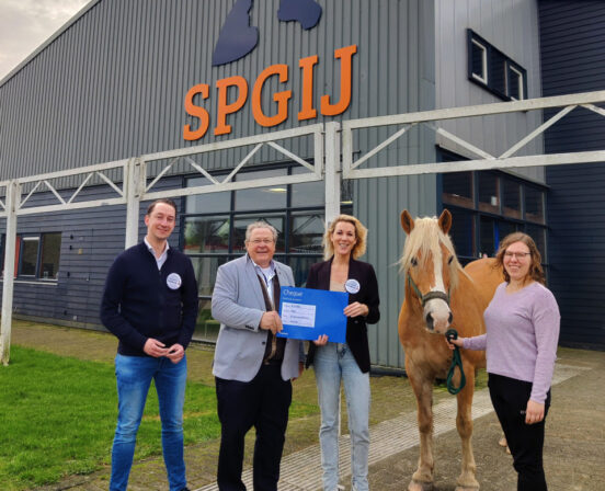 Niek Teune (Rabo), Jan van de Wetering (SPGIJ), Jenneke Palland (Rabo) en Alice Klooster (SPGIJ), poseren buiten voor de manege met de cheque van de Rabobank.